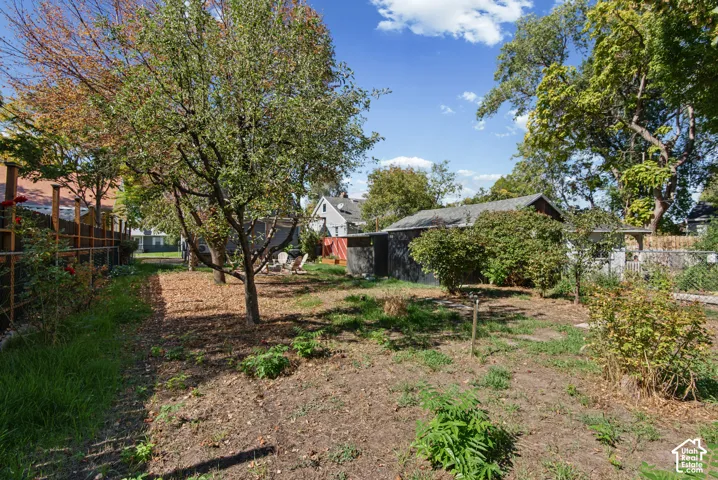 Expansive backyard featuring mature trees, a planted garden area, and a storage structure