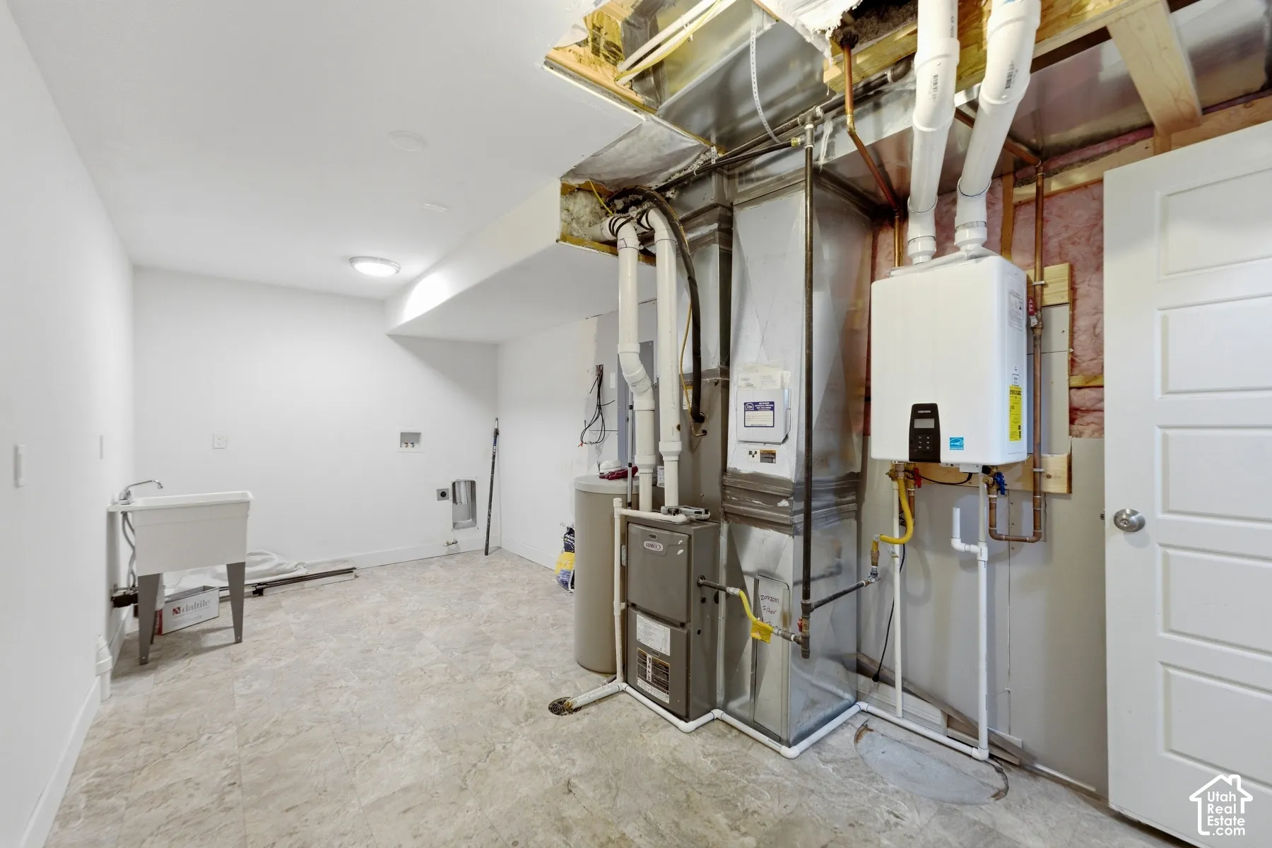 Laundry area with a utility sink, light gray flooring, and a tankless water heater