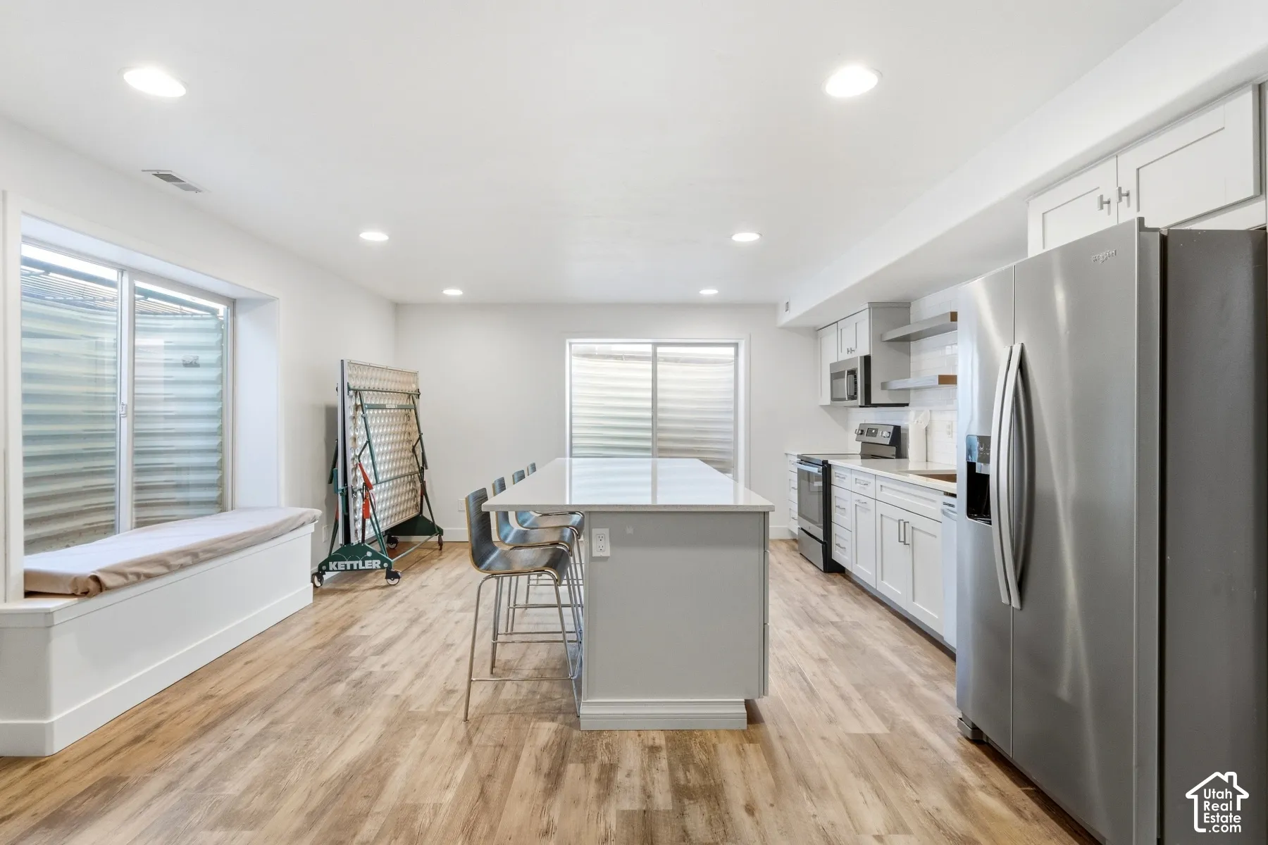 Recessed lighting, wood-finish flooring, built-in window bench, kitchen island with seating, and stainless steel appliances