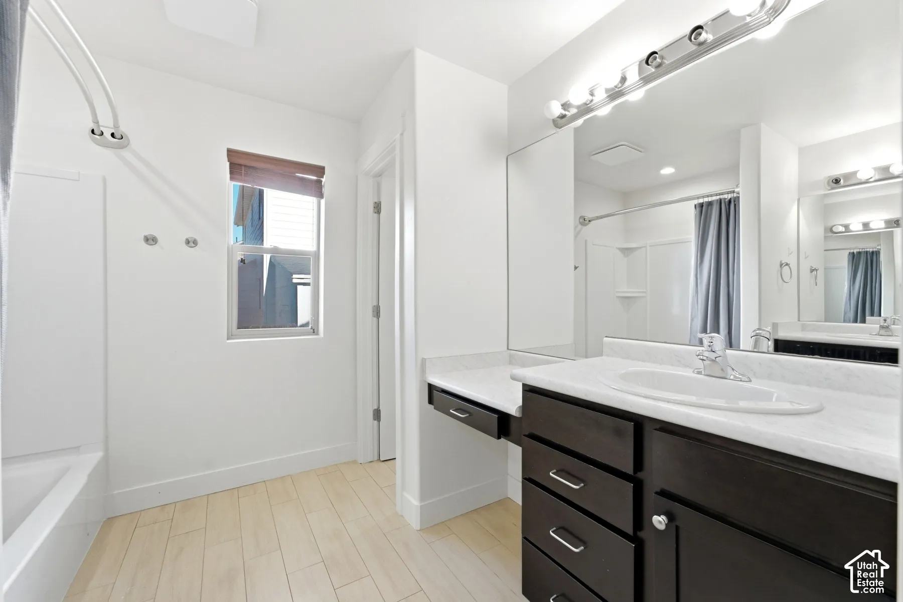 Spa-inspired primary bathroom featuring a dual-sink vanity with dark cabinetry, white quartz countertops, and polished chrome hardware