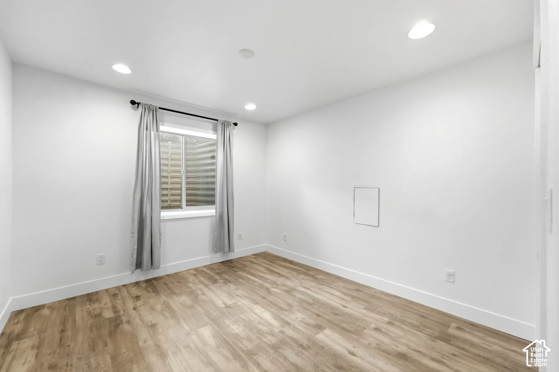Wood-finish flooring, recessed lighting, and a white window frame with a window well