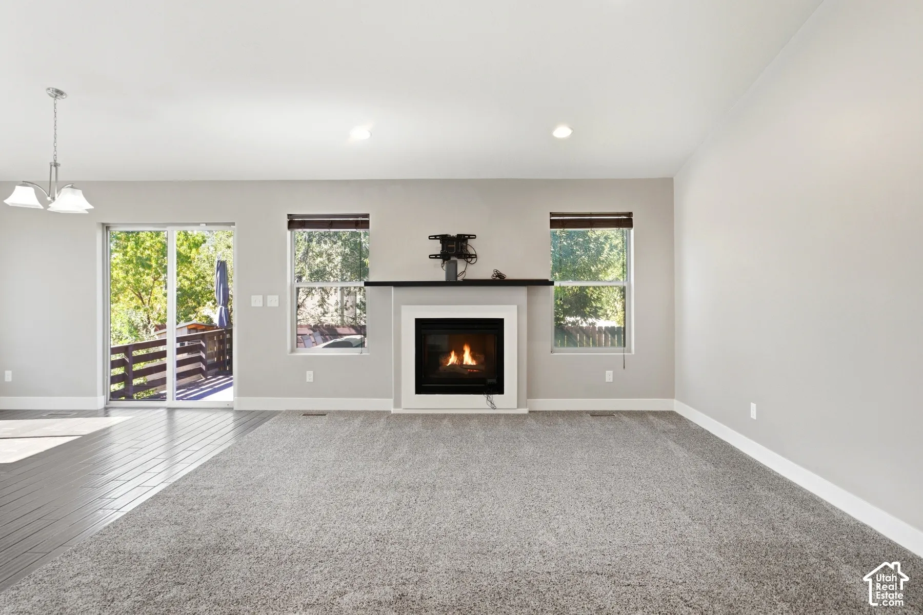 Fireplace with a dark mantle, large sliding glass door, recessed lighting, and mixed flooring