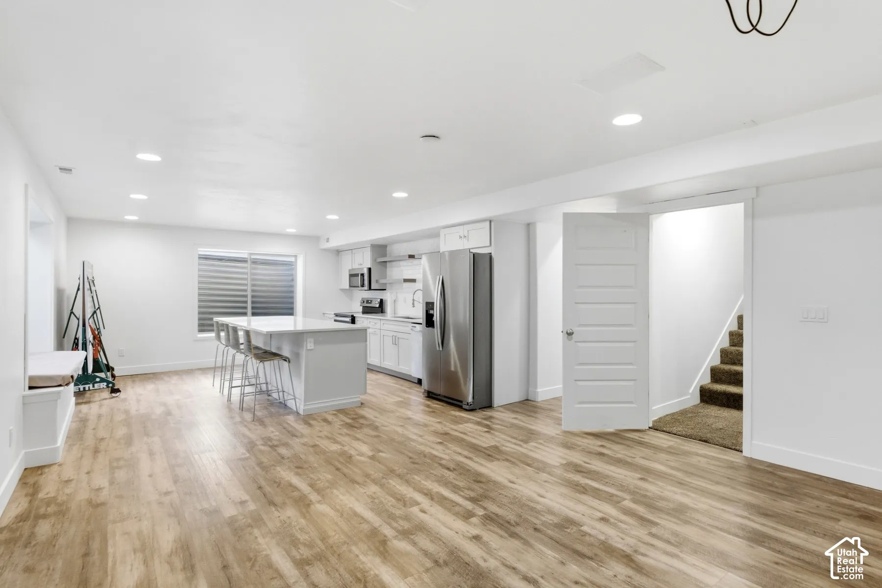 Open concept living area with wood-finish flooring, white cabinetry, a kitchen island, recessed lighting, and a built-in window seat