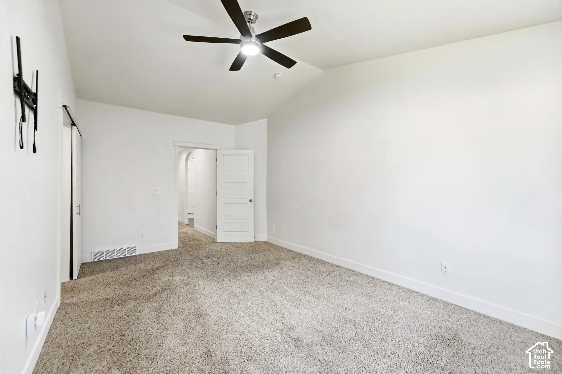 Vaulted ceiling with an attached ceiling fan, neutral carpeting, and white walls