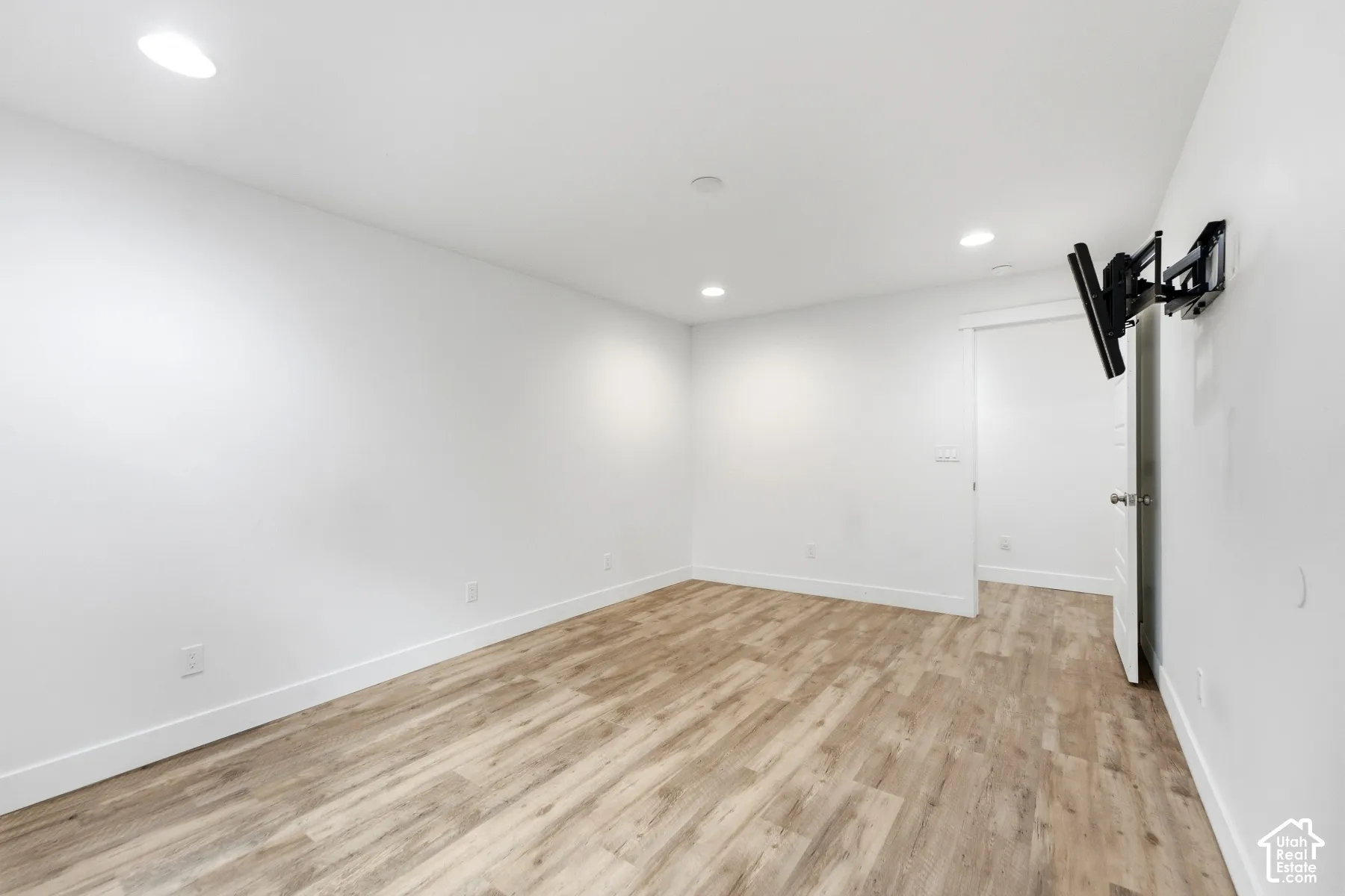 Wood-finish flooring with white baseboards, recessed lighting, and a neutral color palette