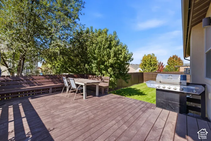 Expansive wood-finish deck with built-in bench seating and a manicured lawn
