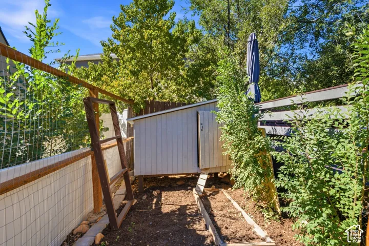 Private backyard retreat featuring mature shade trees, metal storage structure with gated entry, and lush climbing ivy providing natural screening