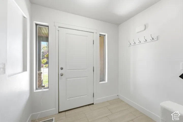 Entryway featuring a paneled door, vertical sidelight windows, and light-toned tile flooring