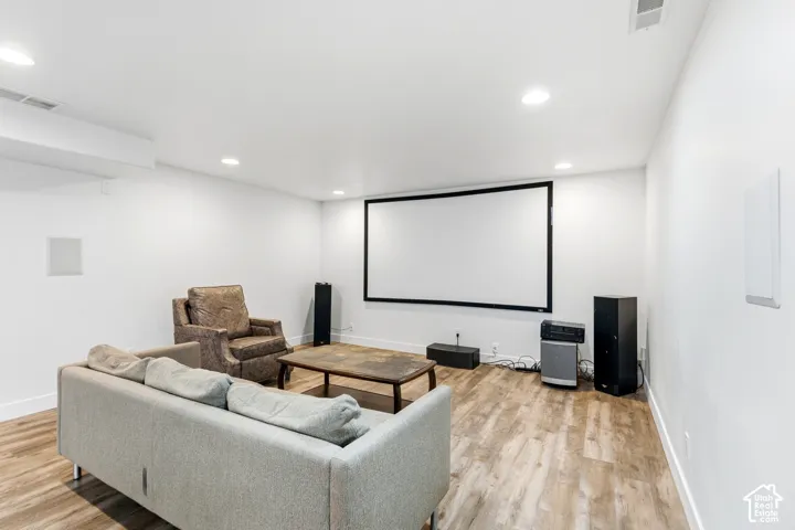 Recessed lighting illuminates the space, featuring a large projection screen and wood-finish flooring