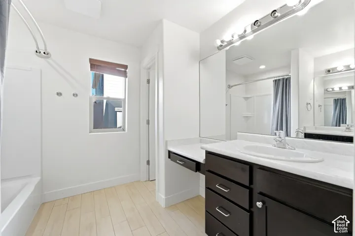 Spa-inspired primary bathroom featuring a dual-sink vanity with dark cabinetry, white quartz countertops, and polished chrome hardware