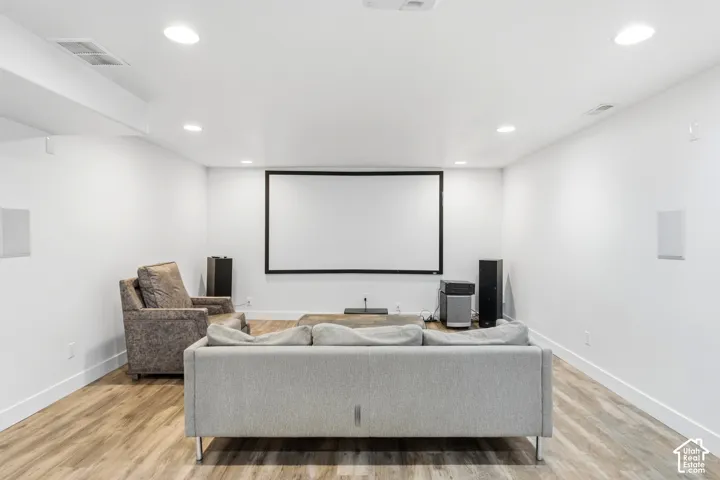 Dedicated media room featuring a projection screen, recessed lighting, and wood-finish flooring
