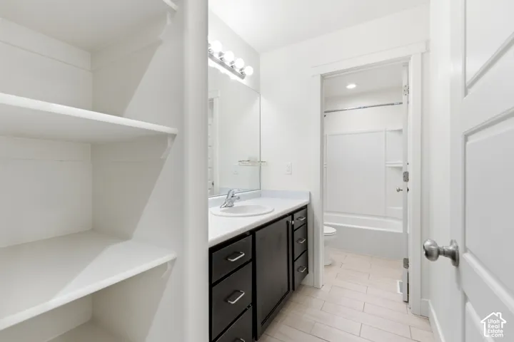 White built-in shelving, dark wood-finish vanity with a white countertop, and a vanity mirror with overhead lighting