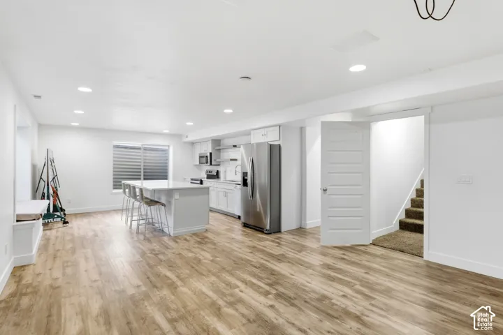 Open concept living area with wood-finish flooring, white cabinetry, a kitchen island, recessed lighting, and a built-in window seat