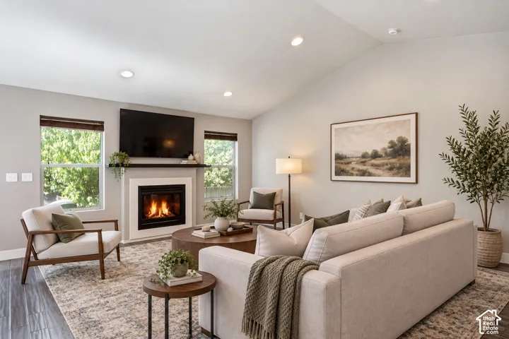 Vaulted ceiling, recessed lighting, and a fireplace with a white mantel and dark wood shelf