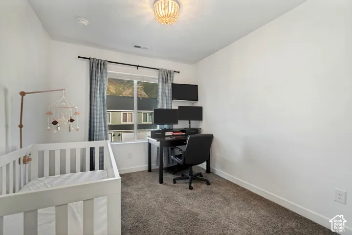Plush carpet flooring, recessed window with dark curtain rod, white walls, and a decorative ceiling light fixture
