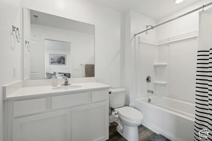 White vanity with a single basin sink, white countertop, and a built-in tub and shower combination with a bright white surround