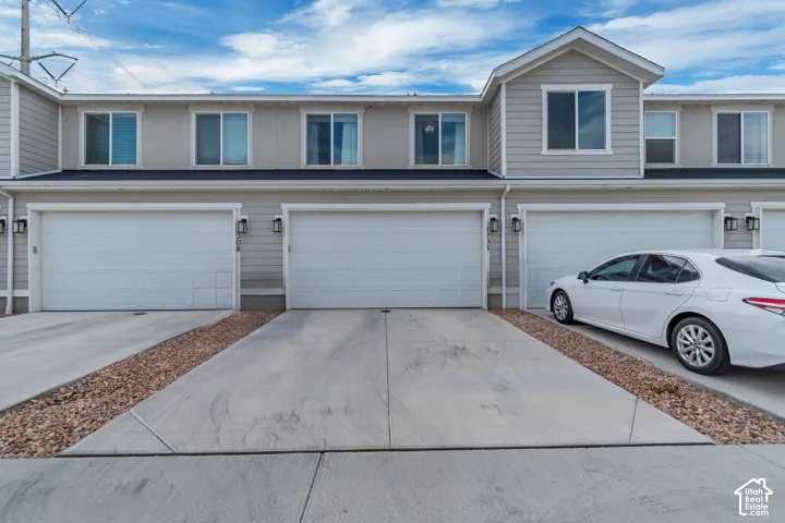 Gray siding exterior with multiple garage bays, individual concrete driveways, and upper-level windows