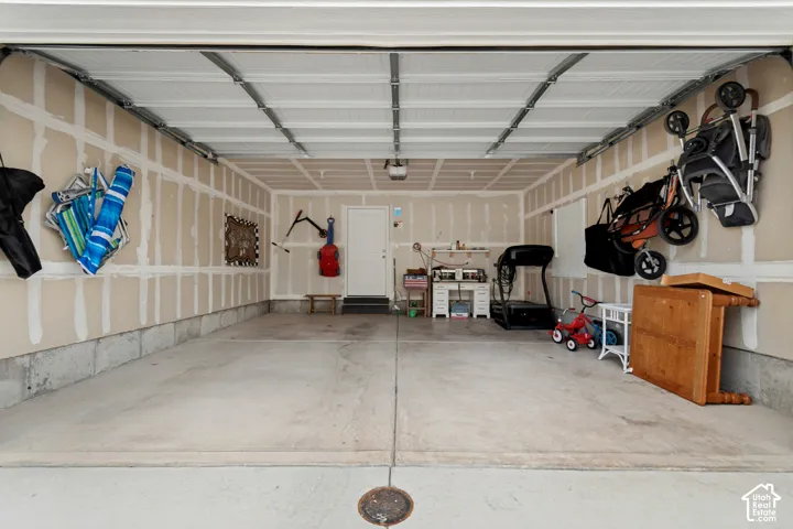 Spacious garage with concrete flooring, exposed wall studs, and a white interior door