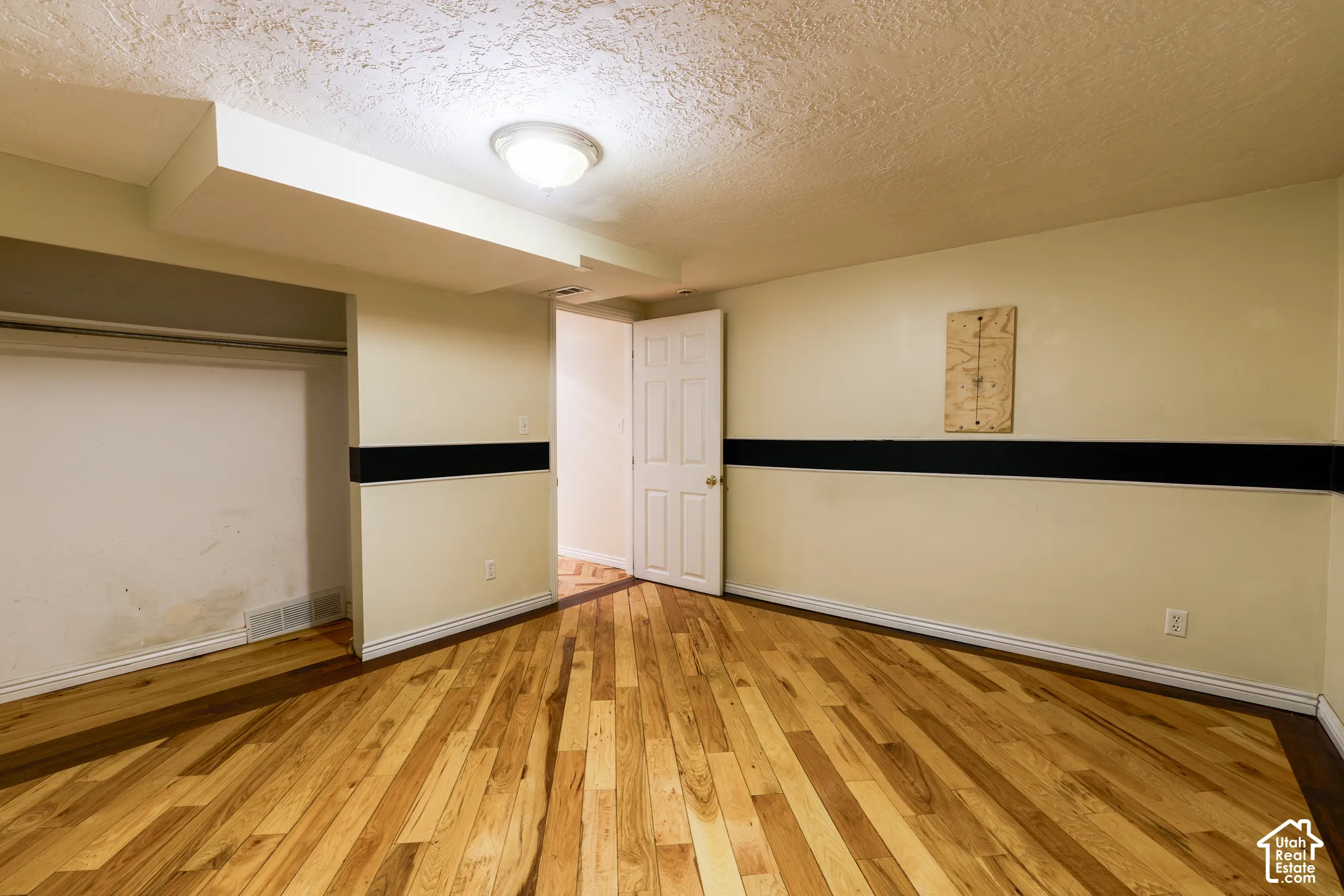 Wood-finish flooring, overhead flush mount light fixture, interior door, and built-in closet space
