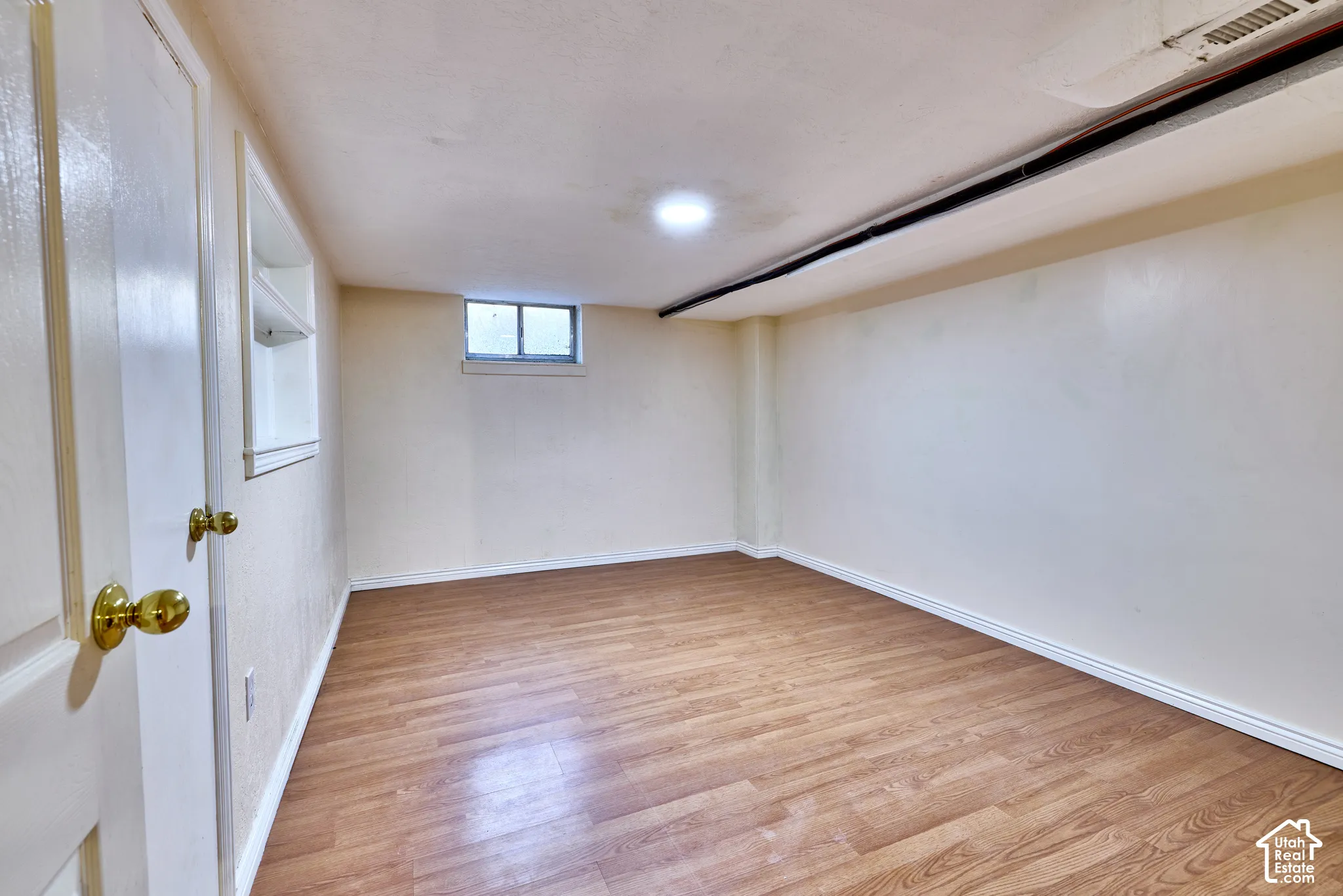 Recessed lighting illuminates the room, featuring wood-finish flooring, a white trim, and a window