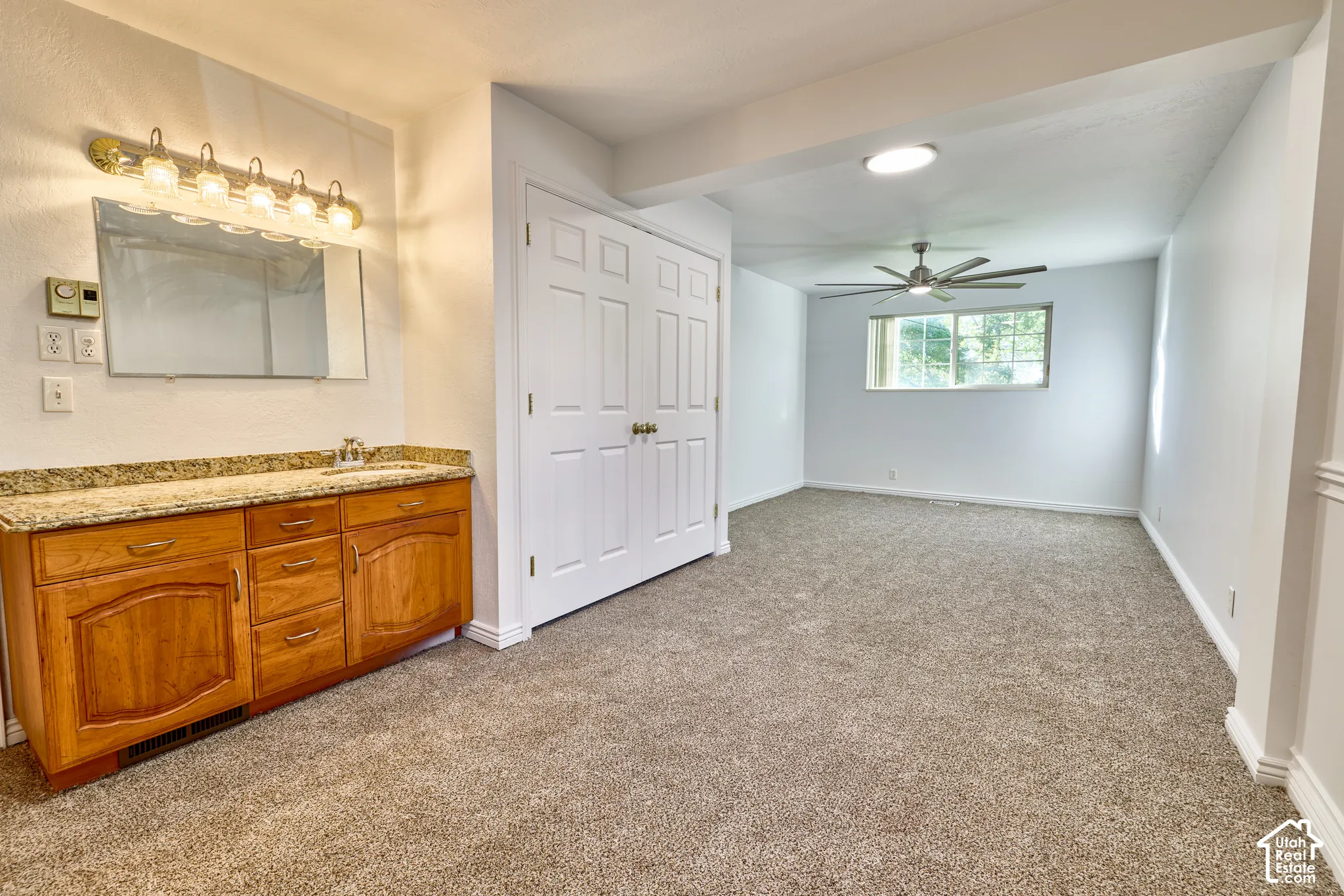 Vanity with granite countertop and integrated sink, dual-door closet with gold-toned hardware, ceiling fan, recessed lighting, and carpeted flooring