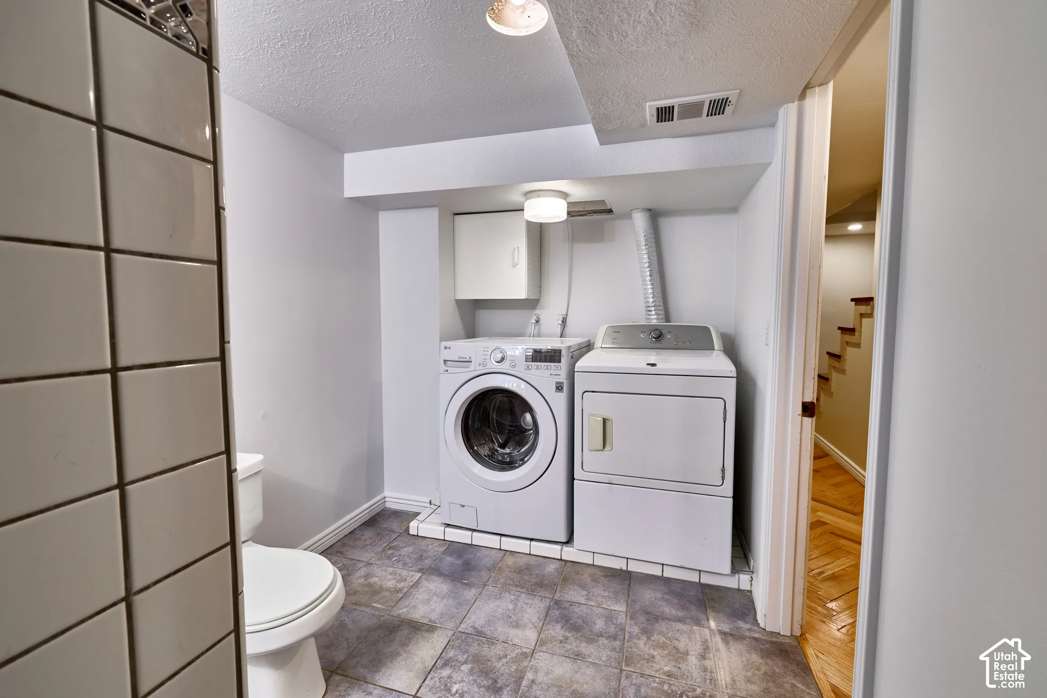 Laundry area featuring a side-by-side washer and dryer, wall-mounted cabinetry, and a ceiling-mounted light fixture