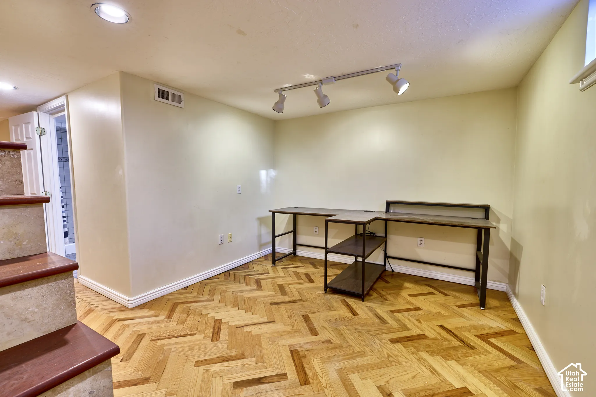 Herringbone wood-finish flooring, recessed ceiling lighting, track lighting, and a window well
