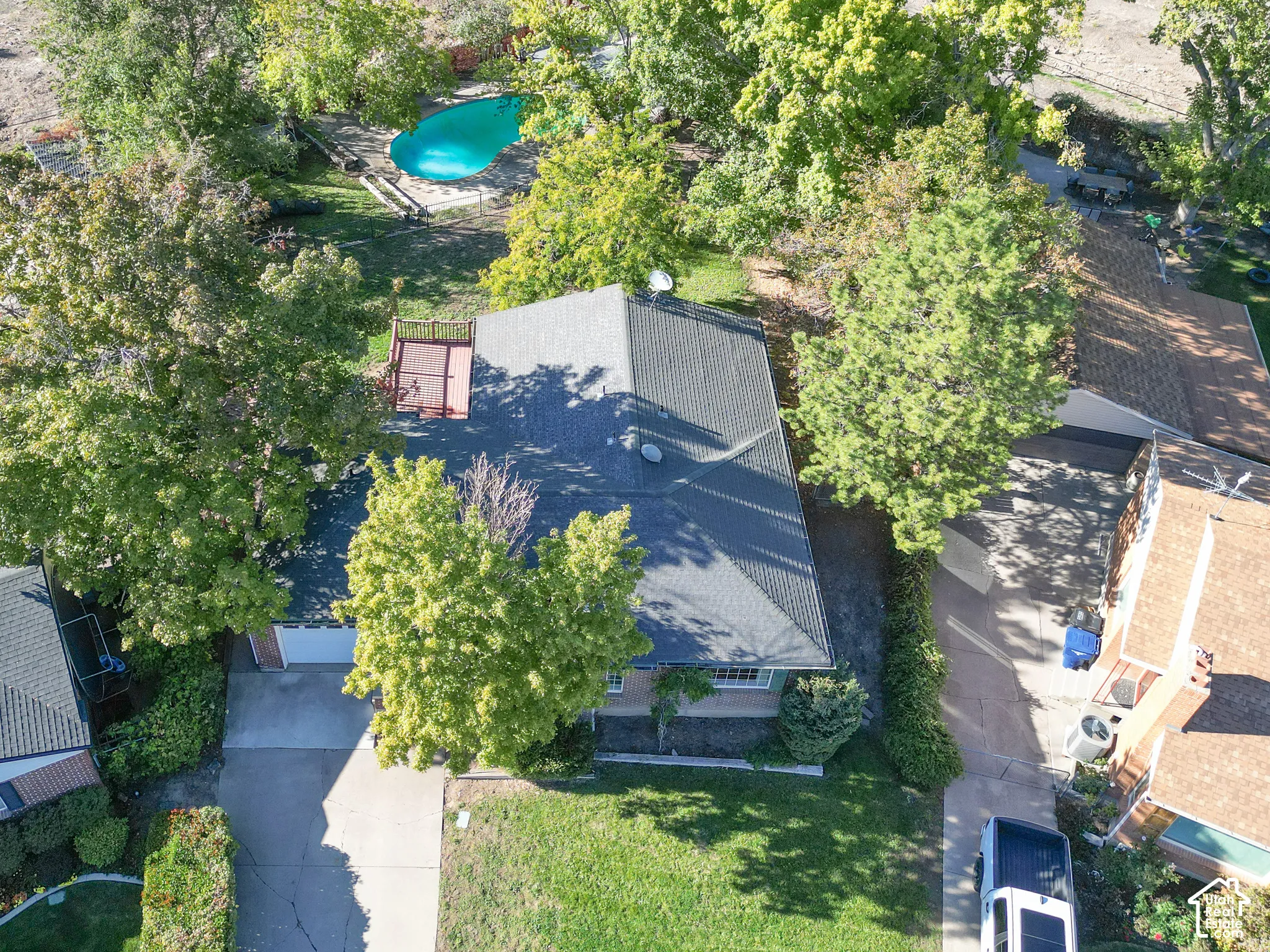 Expansive property featuring a swimming pool, mature trees, a wraparound deck, and an attached garage