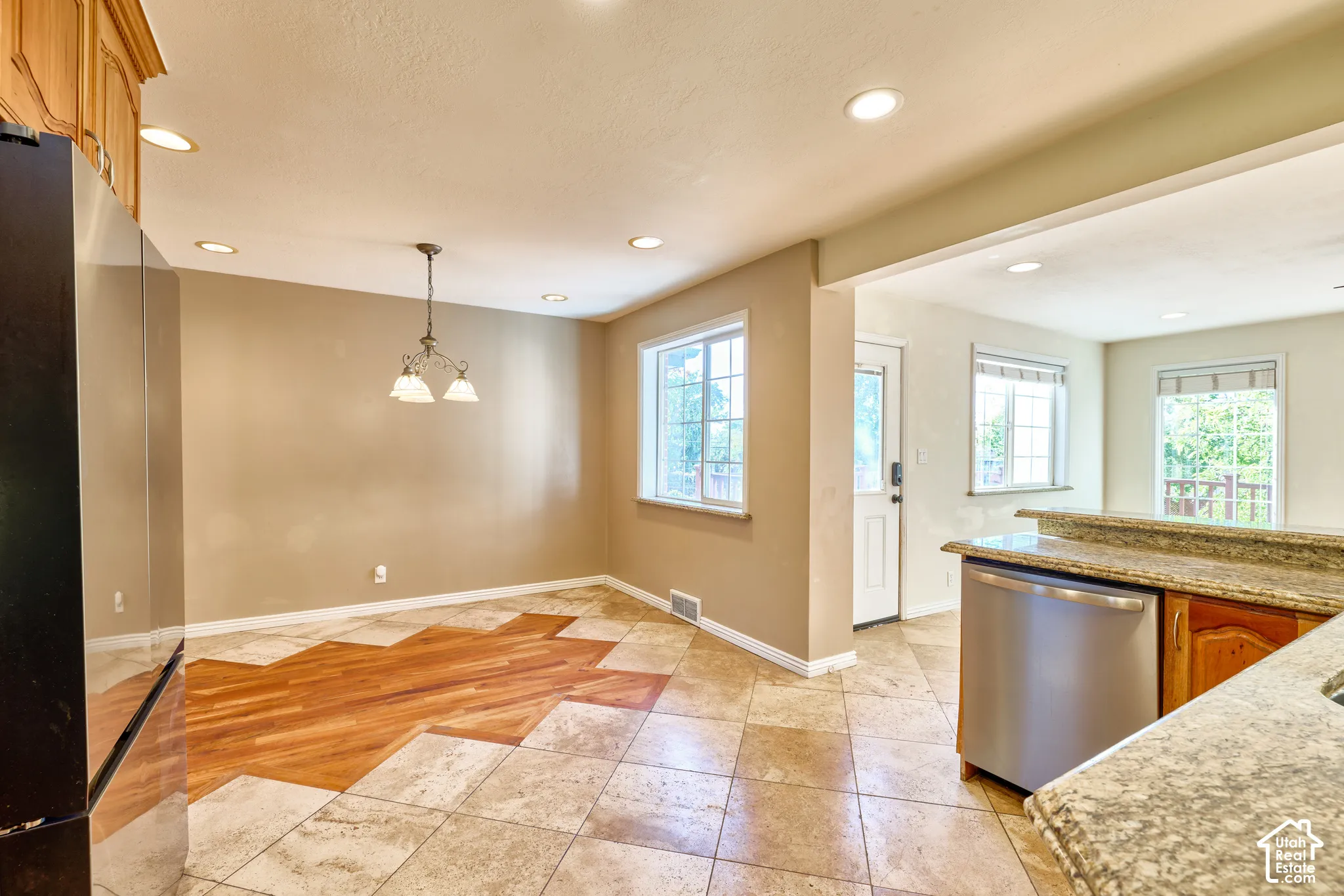 Recessed lighting throughout, two windows with sills, mixed tile and wood-finish flooring, stainless steel dishwasher, and granite countertops