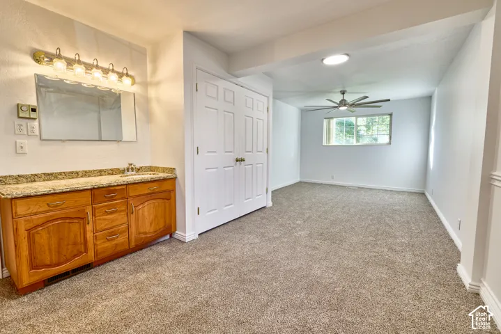 Vanity with granite countertop and integrated sink, dual-door closet with gold-toned hardware, ceiling fan, recessed lighting, and carpeted flooring