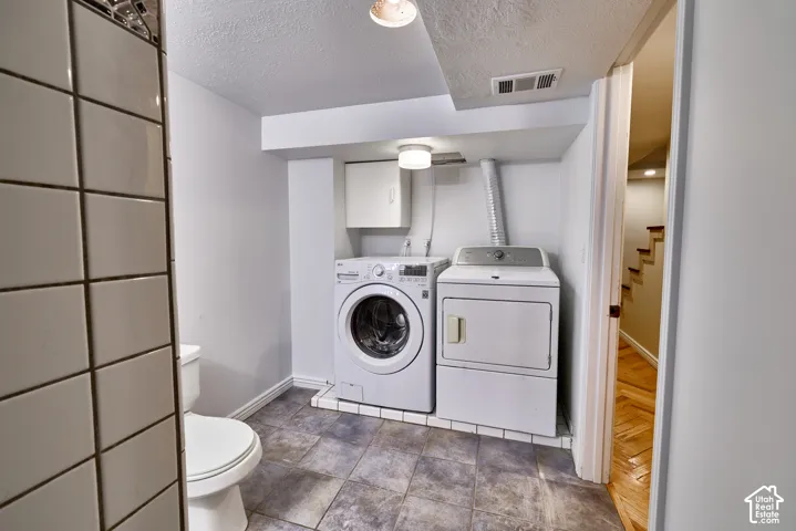 Laundry area featuring a side-by-side washer and dryer, wall-mounted cabinetry, and a ceiling-mounted light fixture