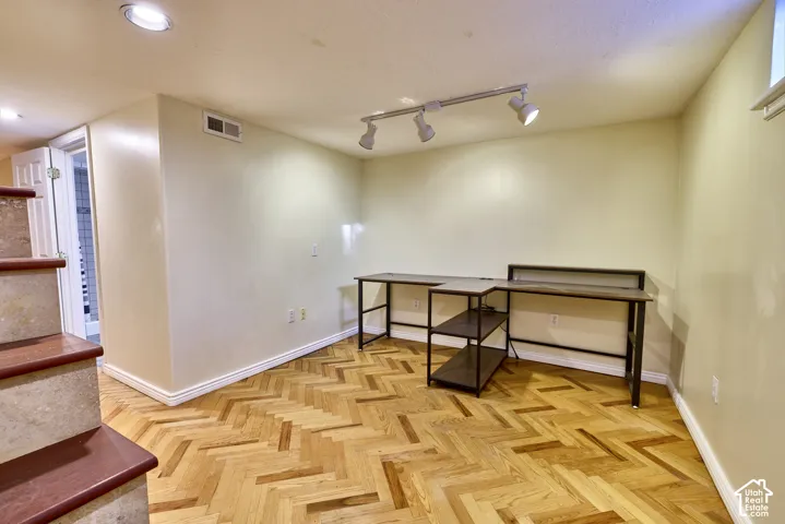 Herringbone wood-finish flooring, recessed ceiling lighting, track lighting, and a window well