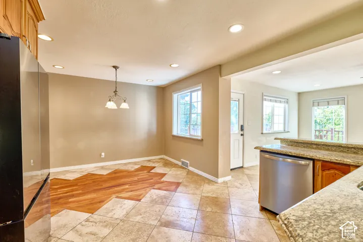 Recessed lighting throughout, two windows with sills, mixed tile and wood-finish flooring, stainless steel dishwasher, and granite countertops