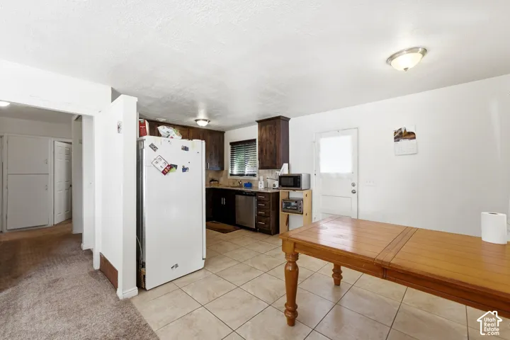 Kitchen featuring tile flooring, dark wood-finish cabinetry, stainless steel appliances, and a white paneled door