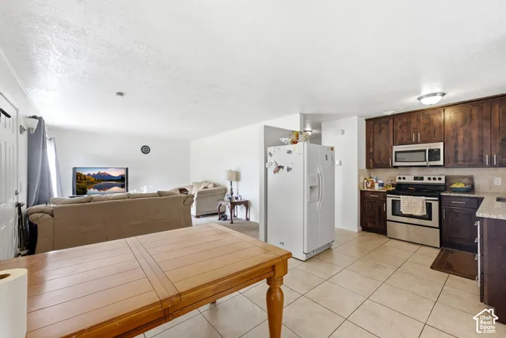 Kitchen featuring dark wood-finish cabinetry, stainless steel appliances, and light-toned tile flooring