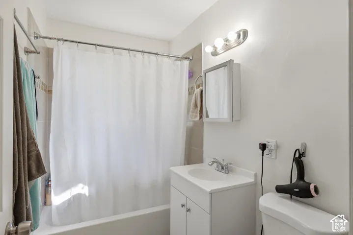 Bathroom featuring a white vanity with integrated sink, chrome faucet, medicine cabinet, and a shower-over-tub combination