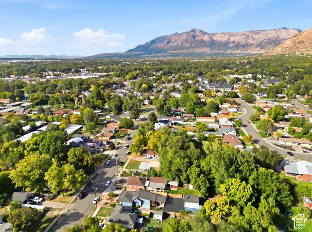 Expansive residential area featuring numerous mature trees, paved streets, and a prominent mountain range backdrop
