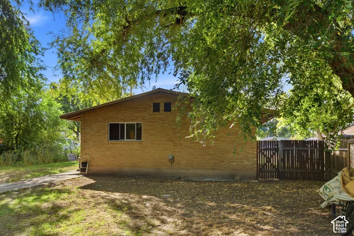 Brick exterior with a gabled roofline, multiple windows, and partial fencing
