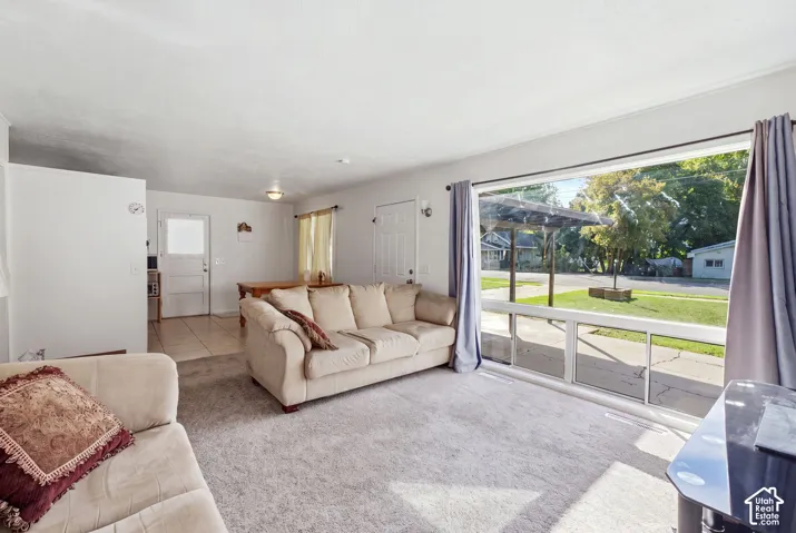 Expansive picture window, light-colored carpeting, white walls, recessed ceiling light, and tiled flooring