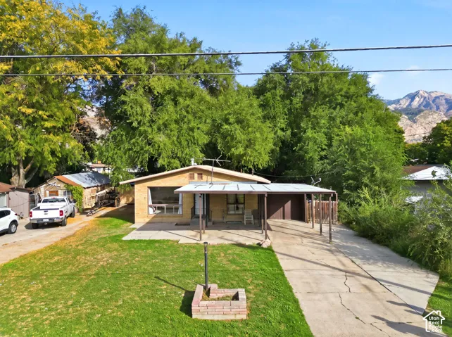 Brick exterior, covered carport, concrete driveway, mature trees, mountain range
