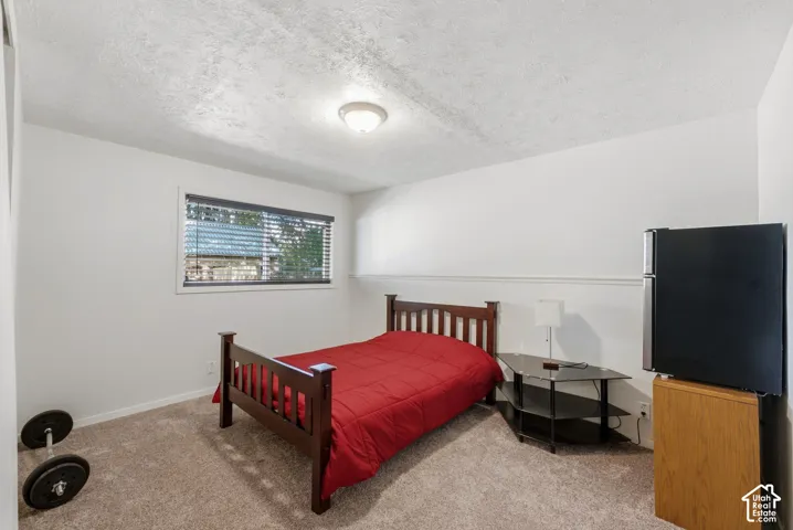White walls with chair rail detailing, textured ceiling, and a large window with blinds