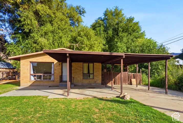 Brick exterior with brown trim, covered carport, and a prominent front picture window