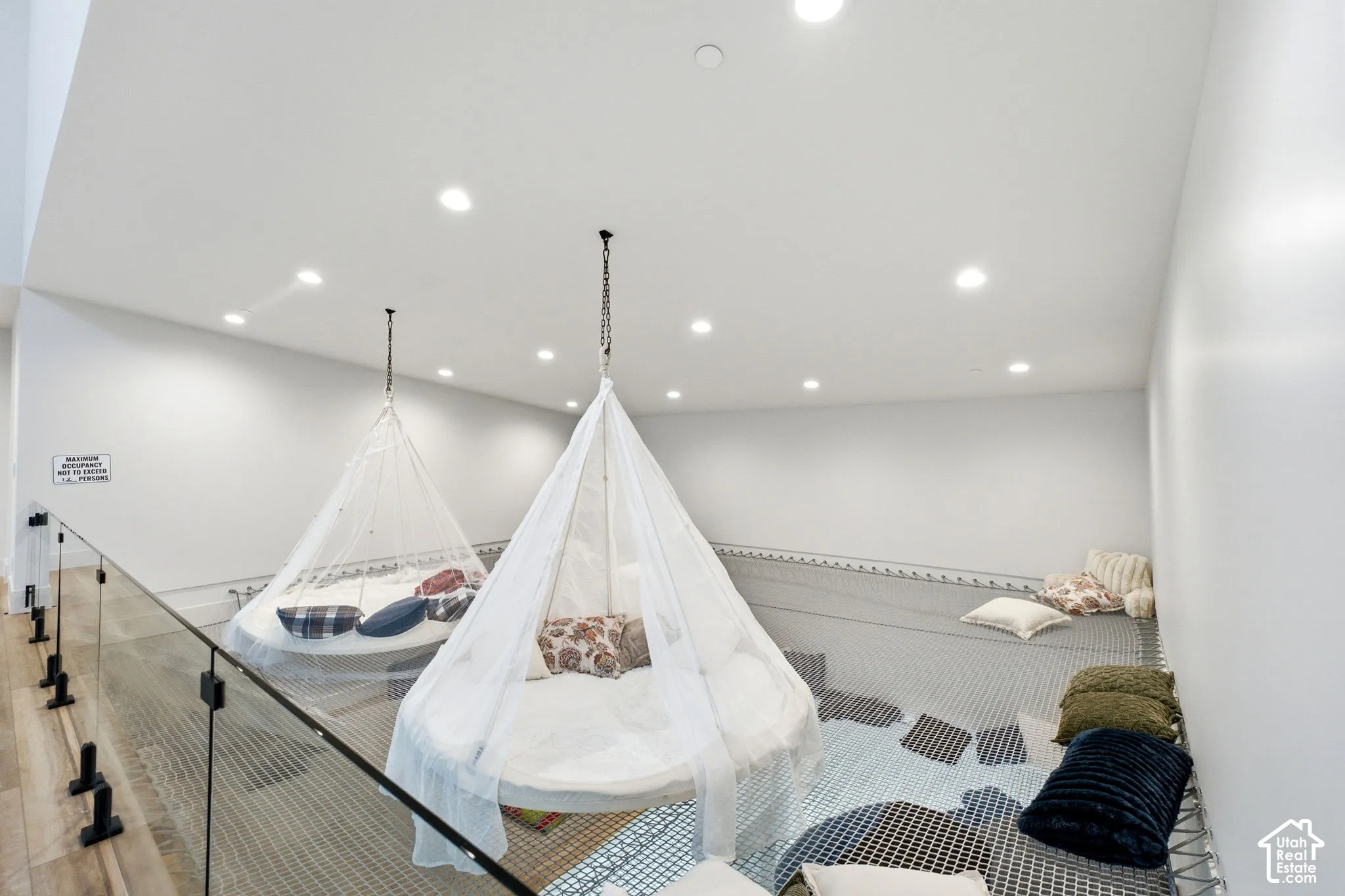 Loft area with recessed lighting, glass railing, and wood-finish flooring