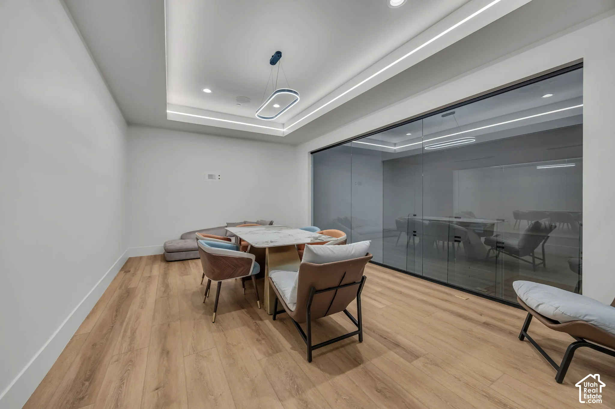 Recessed lighting, wood-finish flooring, accent ceiling lighting, and a full-height glass wall