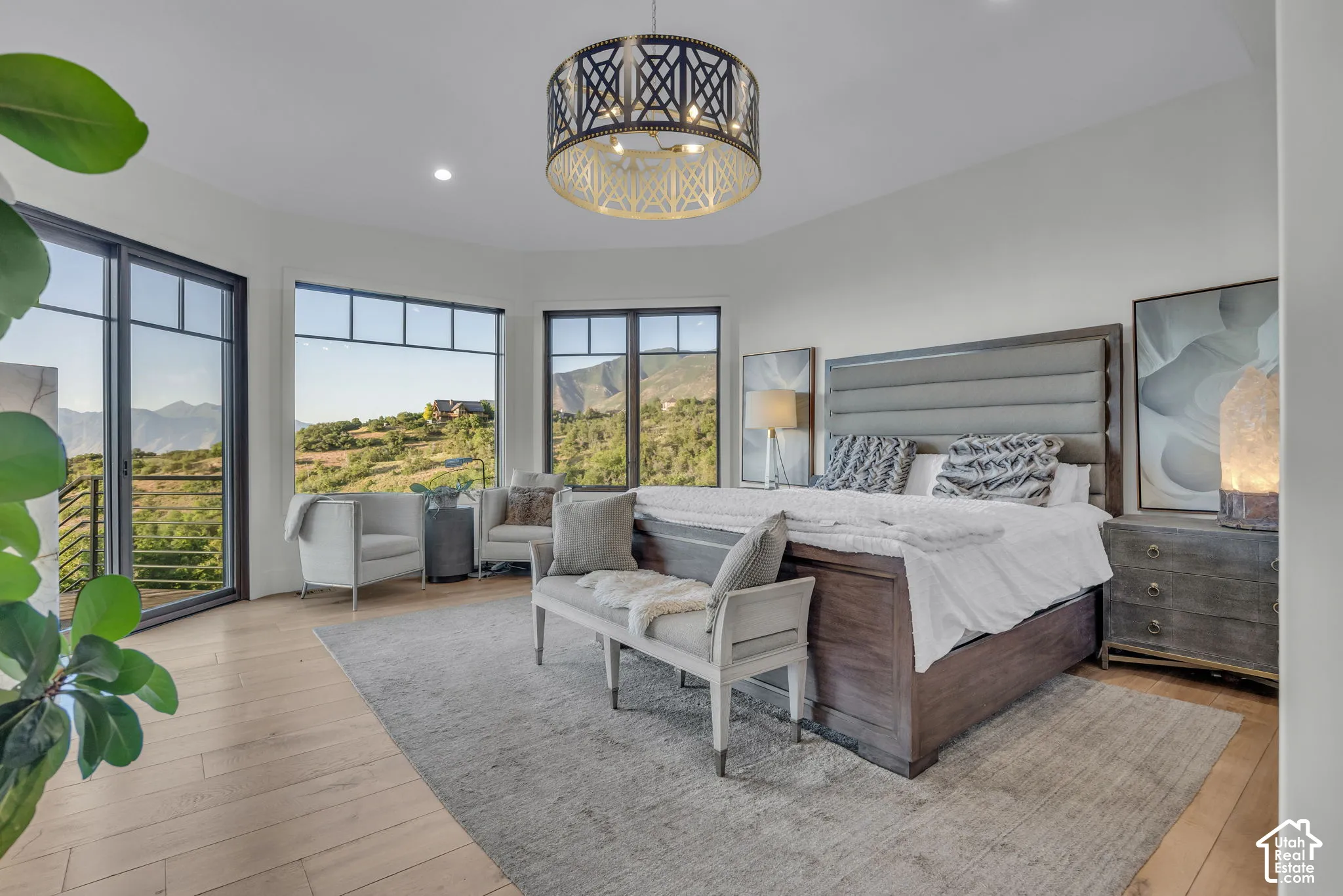 Expansive windows with mountain scenery, light wood-finish flooring, and a decorative ceiling fixture
