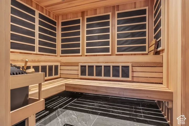 Cedar-lined sauna with tiered wood benches, dark-toned wall panels, and dark-toned floor tiling