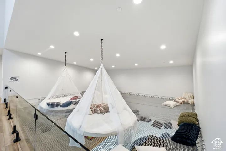 Loft area with recessed lighting, glass railing, and wood-finish flooring