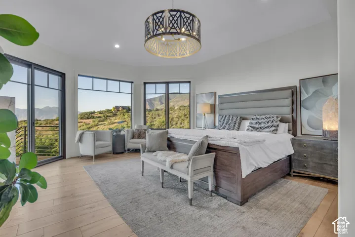 Expansive windows with mountain scenery, light wood-finish flooring, and a decorative ceiling fixture