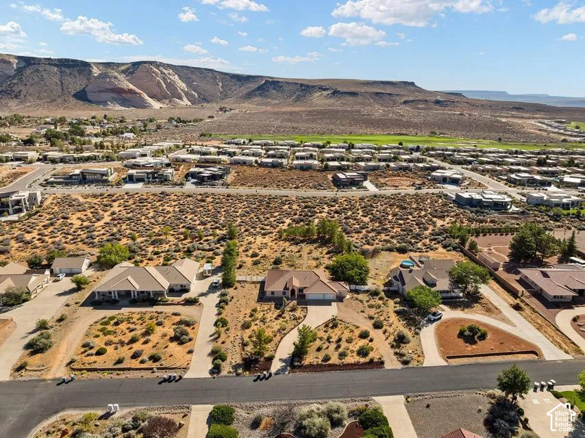 Expansive desert landscape with residential development, a distant mountain backdrop, and a golf course