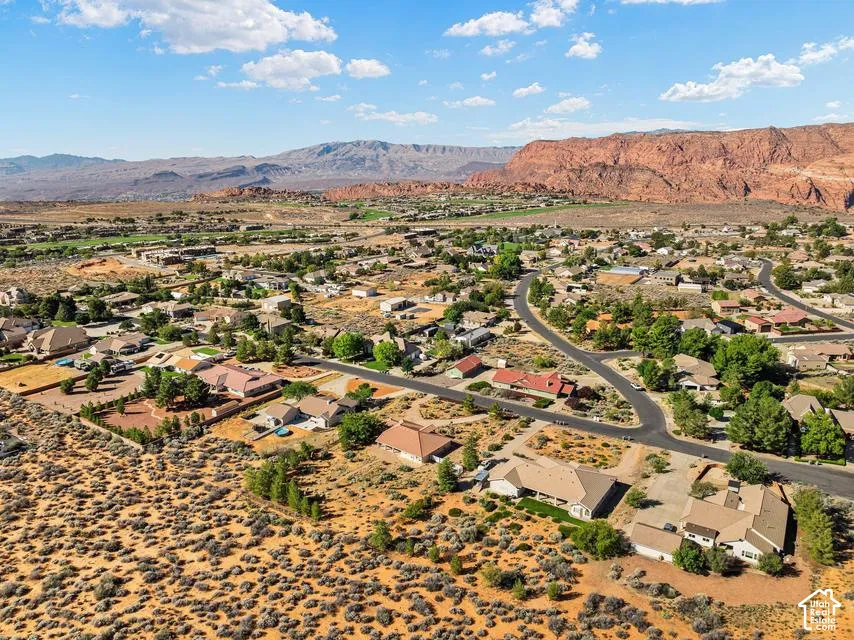 Residential development with winding streets and established landscaping, set against a backdrop of distant mountains